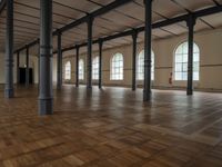 a very big nice and empty building with wood floors and tall columns and lots of windows