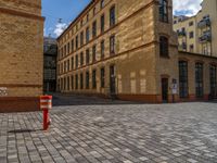 a sidewalk with chairs next to the brick building on the side, some have stairs and some buildings in the background