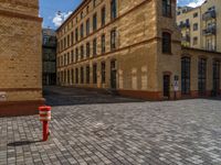 a sidewalk with chairs next to the brick building on the side, some have stairs and some buildings in the background