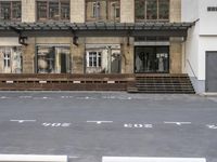 an empty building with signs on the street and people on bikes in traffic passing by