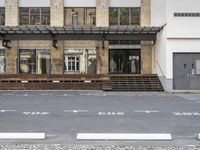 an empty building with signs on the street and people on bikes in traffic passing by