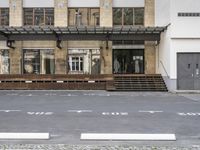 an empty building with signs on the street and people on bikes in traffic passing by