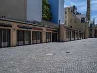 the sidewalk is paved with stones and has a bench in front of it, with no people inside