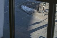 a street with parked vehicles at a stoplight and snow on the ground, taken from a window