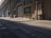 an abandoned factory with lots of windows and sign post with a street below it that reads no parking on one side