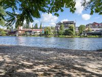 two people on a bench in front of the river and other houses behind them that is the water with a brown sand surface