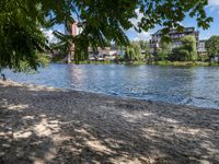 two people on a bench in front of the river and other houses behind them that is the water with a brown sand surface