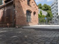 a building with brick walls is next to an area with trees in it, with a gate in front