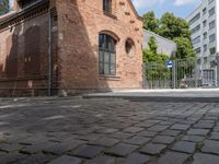 a building with brick walls is next to an area with trees in it, with a gate in front