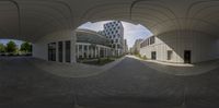 an arched walkway leads to several large buildings with doors and walkways in each direction