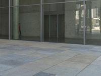 a lone person walking by large glass windows next to a building with no one inside