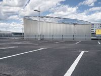 parking spaces with white lines and big domed building in distance on a cloudy day with fluffy clouds overhead