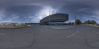 a fish - eye lens photo of a city with traffic passing by the building on a cloudy day