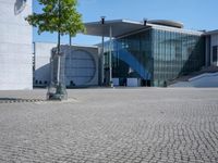 a building with multiple stories and glass walls at its entrance on a cobblestone surface