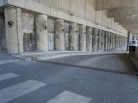 the parking garage of an old concrete building has a bunch of large pillars sticking out