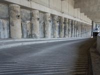 the parking garage of an old concrete building has a bunch of large pillars sticking out