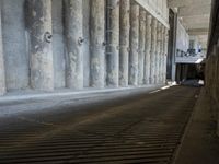 the parking garage of an old concrete building has a bunch of large pillars sticking out