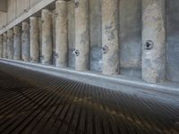 the parking garage of an old concrete building has a bunch of large pillars sticking out