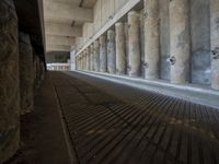 the parking garage of an old concrete building has a bunch of large pillars sticking out