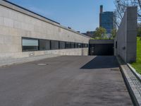 an empty parking lot next to an unfinished wall and parking garages at the edge of a park