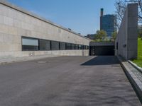 an empty parking lot next to an unfinished wall and parking garages at the edge of a park