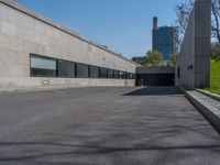 an empty parking lot next to an unfinished wall and parking garages at the edge of a park