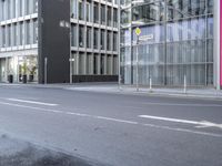 a large building is reflected in the side of the street that goes along this narrow road