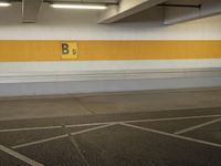 an empty parking lot with a yellow stripe on it's wall and two white lights