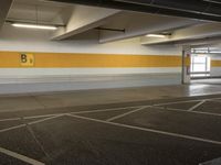an empty parking lot with a yellow stripe on it's wall and two white lights