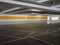 an empty parking lot with a yellow stripe on it's wall and two white lights