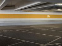 an empty parking lot with a yellow stripe on it's wall and two white lights