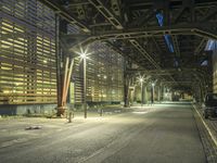 people are riding on benches underneath an elevated bridge over a street at night in the city