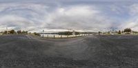 fish eye view of a wide open roadway with a lake and city behind it from a convex image