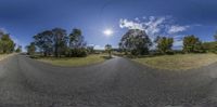 a fisheye view of an empty road with some trees on either side of it