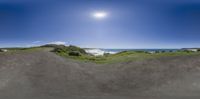 the view from inside a skateboard ramp looking down at the water and a bright sun on a blue sky above