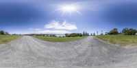 a view of an empty dirt road from a fisheye lens, with a grassy landscape