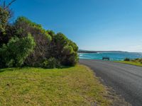 the road is beside the grassy path with the ocean in the background it seems to be empty