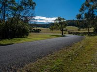 a country road runs through a valley surrounded by wooded woods, grass and trees,