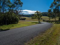 a country road runs through a valley surrounded by wooded woods, grass and trees,