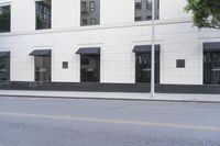 a tree is next to a building with windows and black awnings on it