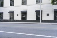 a tree is next to a building with windows and black awnings on it