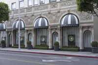 the entrance to the hotel with trees and bushes near it on a street corner near the sidewalk