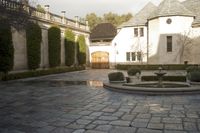 a view of a courtyard with a fountain, water feature and bushes growing in the distance