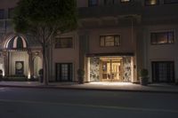 the entrance to a large hotel at night with street lights shining on the walls and doors