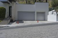 two white garages and one open door next to a street lined with orange cones