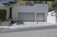 two white garages and one open door next to a street lined with orange cones