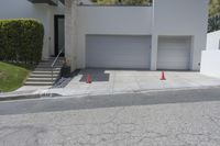 two white garages and one open door next to a street lined with orange cones