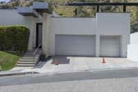 two white garages and one open door next to a street lined with orange cones