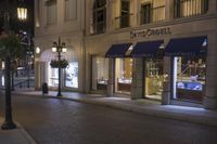 a store is displayed on the sidewalk of this town street at night in a city