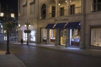 a store is displayed on the sidewalk of this town street at night in a city